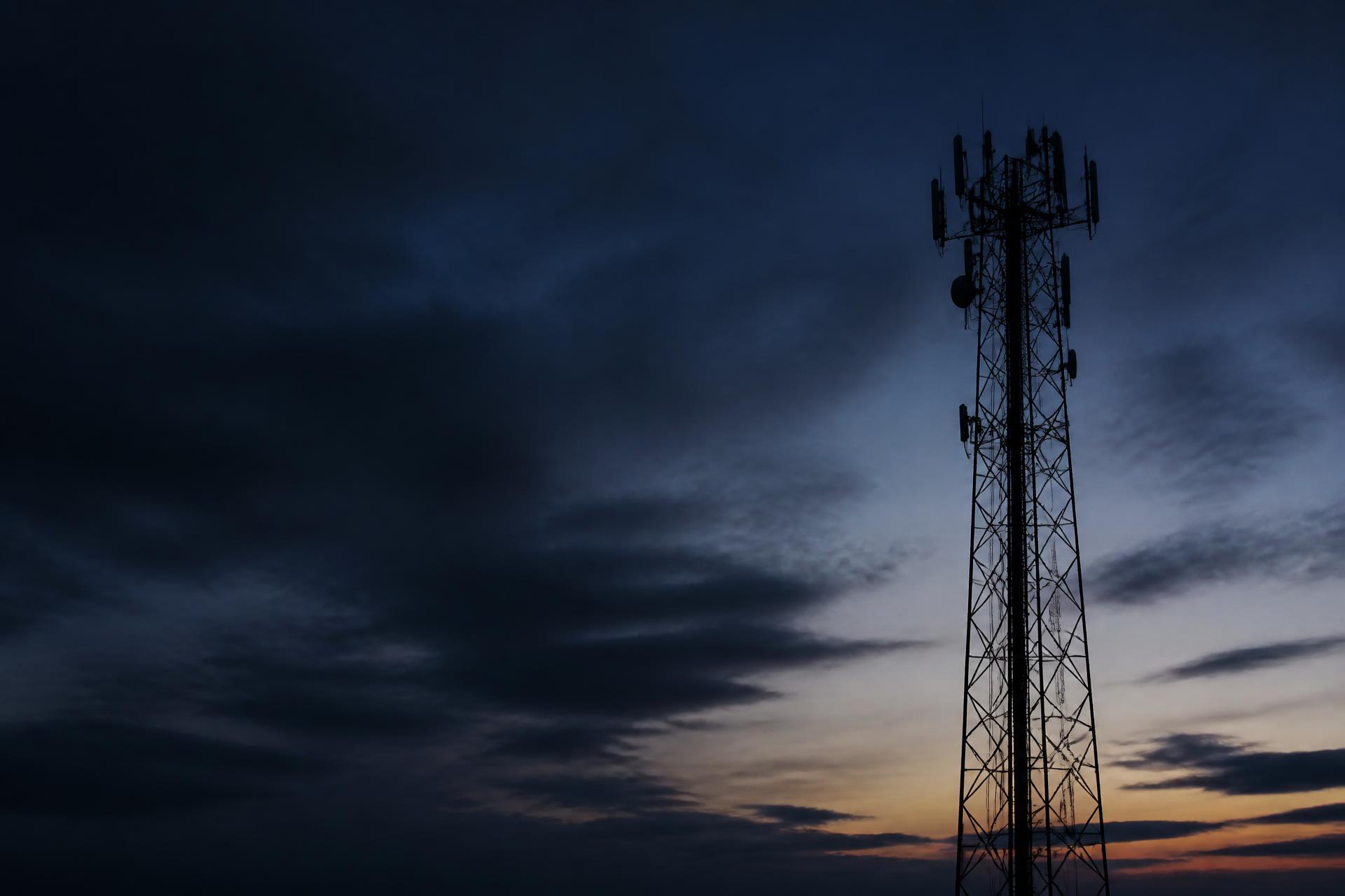 Tower climber working high on a cell tower at dusk